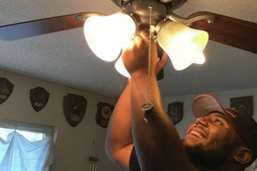 Man fixing ceiling light with a smile.