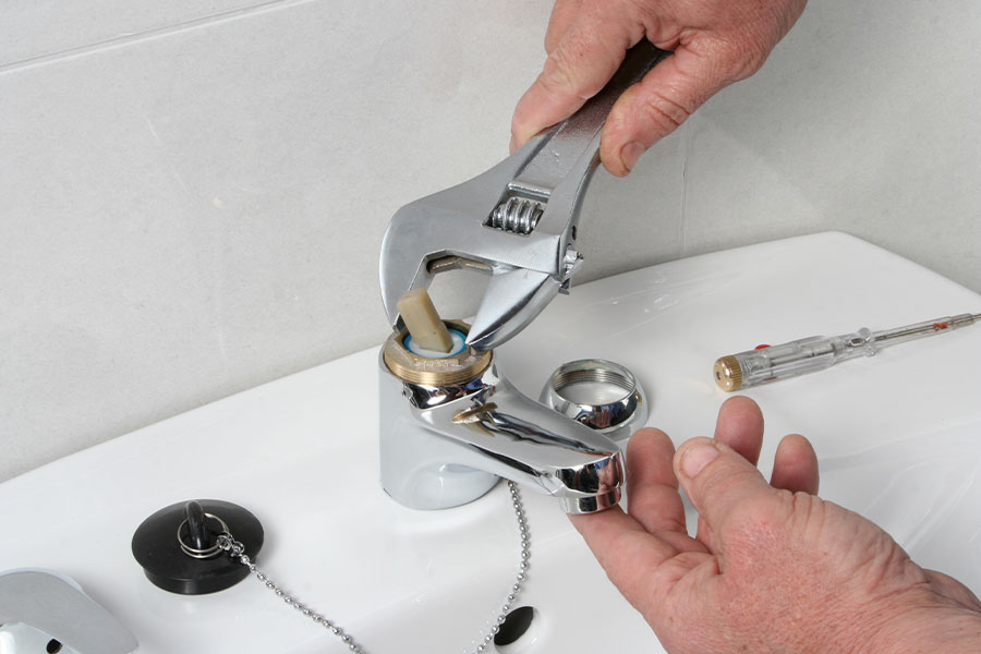Repairing faucet with wrench and screwdriver.