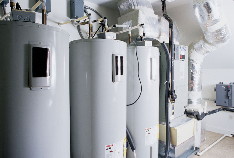 Three gray water heaters in a utility room