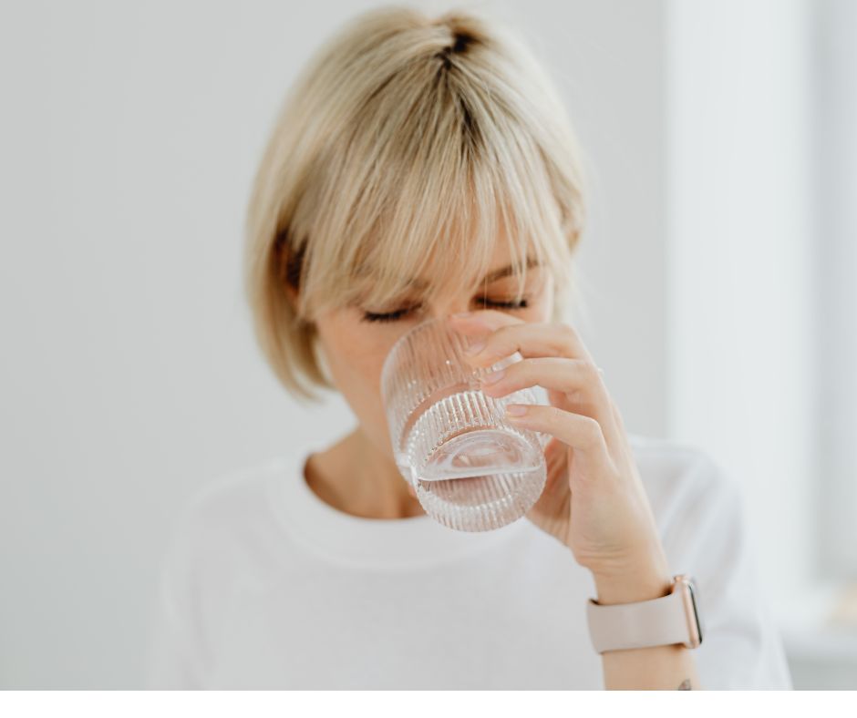 blond woman drinking from clear glass of water