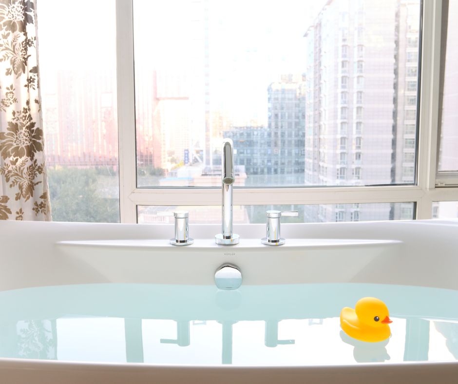 tub filled with water and floating rubber duck with view of the city