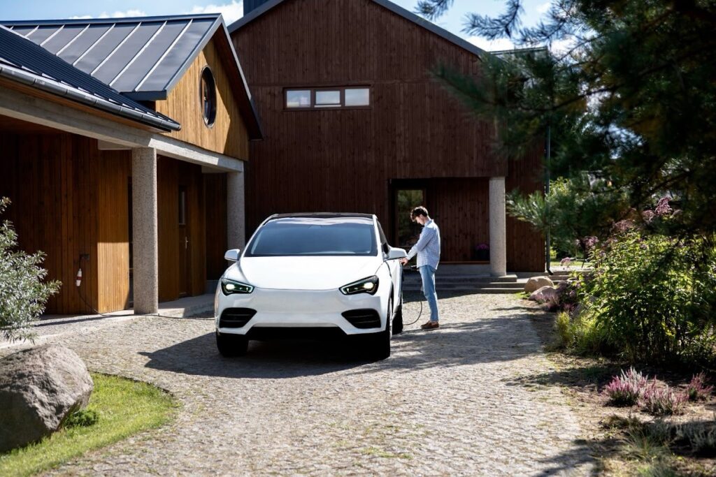 Person charging a white electric vehicle in the driveway