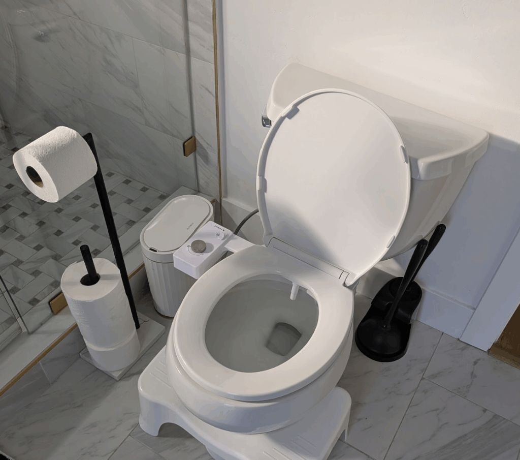 A clean white toilet with a bidet attachment installed in a bathroom.