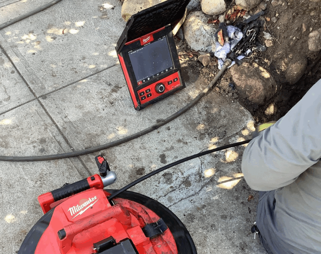 A red diagnostic monitor and cable reel are being used on-site for a plumbing pipe inspection.