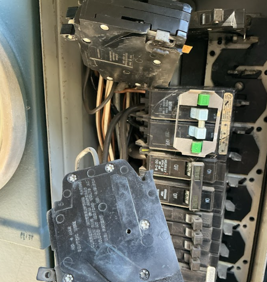 Electrical panel with circuit breakers disconnected and pulled away from the bus bar.