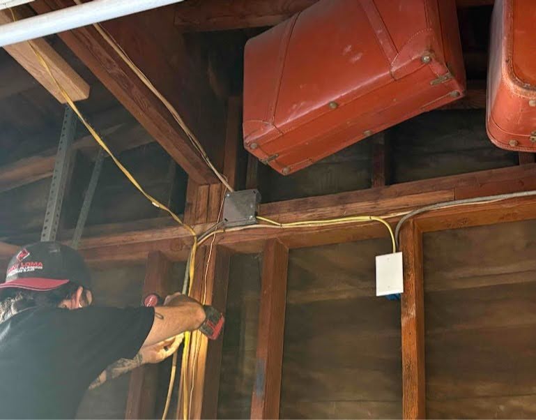 Electrician working on the yellow electrical conduit and wiring in the exposed ceiling