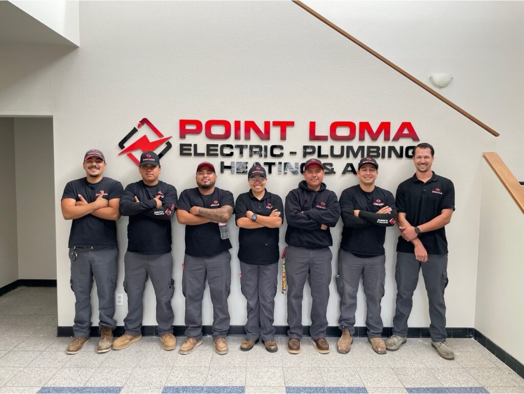 A group of technicians standing in front of the Point Loma company logo
