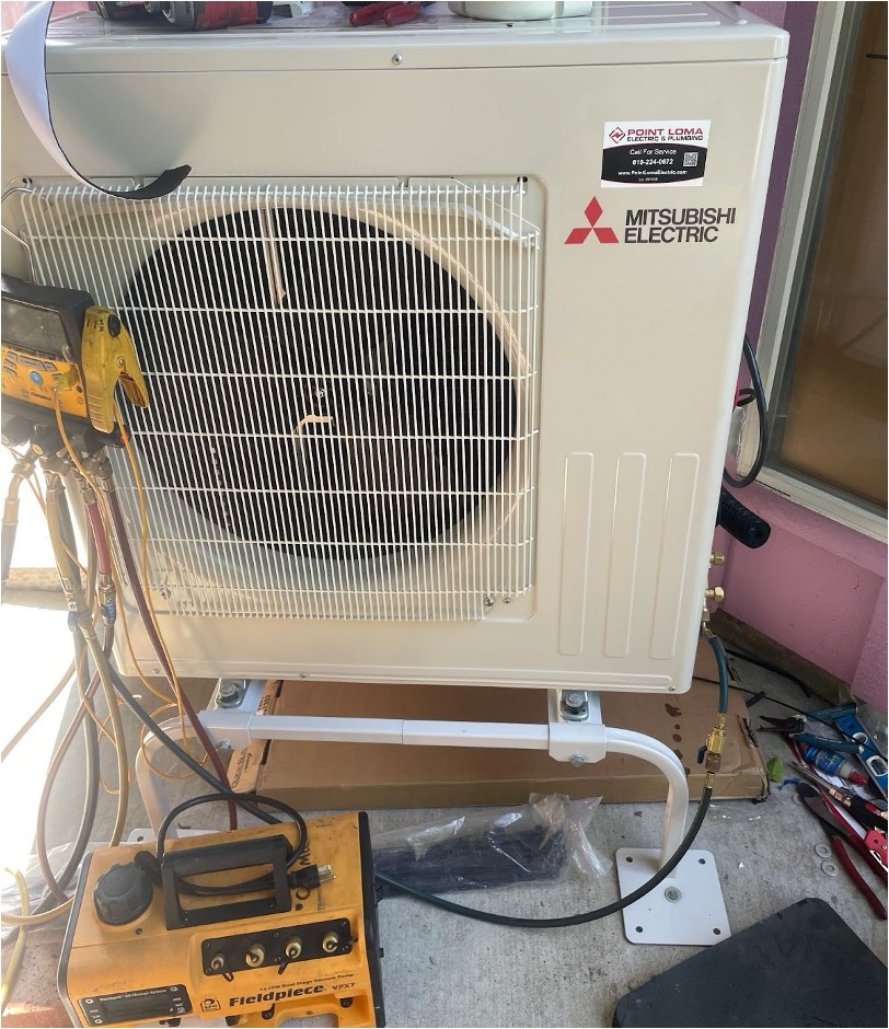 A split AC condenser unit is being serviced with a vacuum pump and manifold gauges