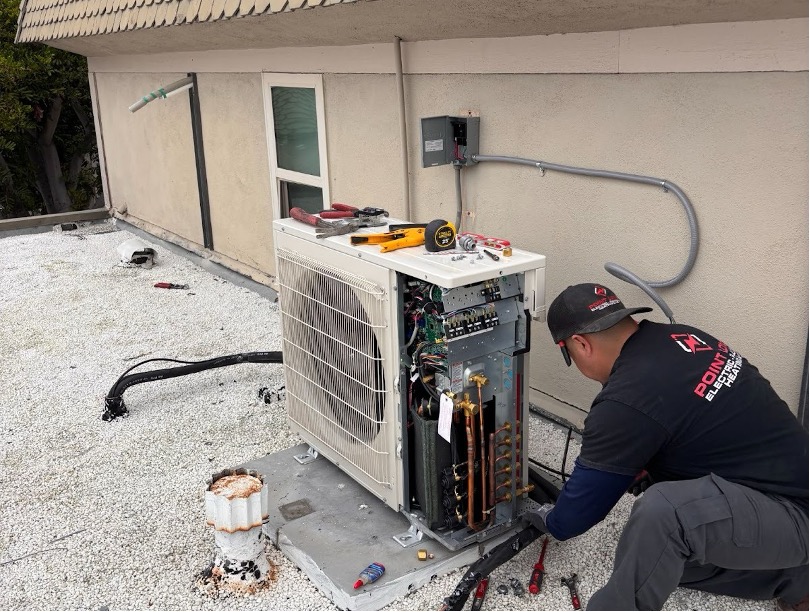 An outdoor AC condenser is being worked on by a Point Loma technician