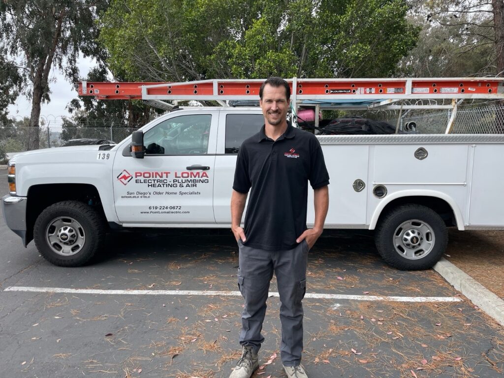 Point Loma technician standing in front of a company truck equipped with ladders and tools.