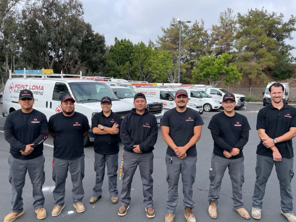 Seven Point Loma technicians in uniforms standing in front of company service vans