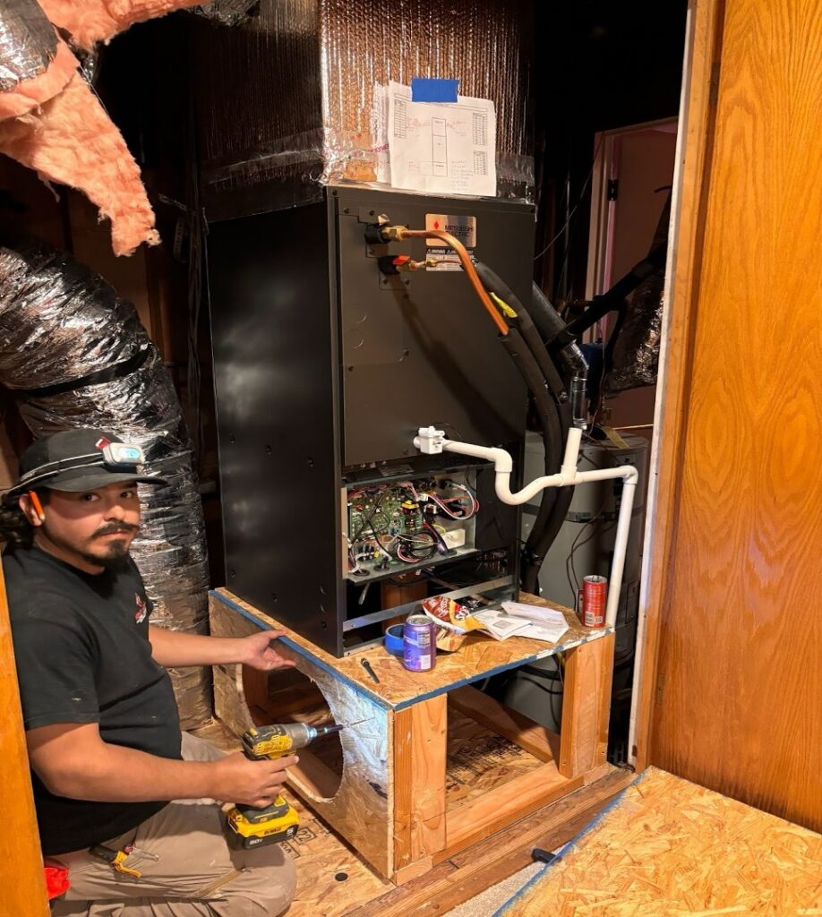 Technician installing a new air handler unit on a wooden platform.