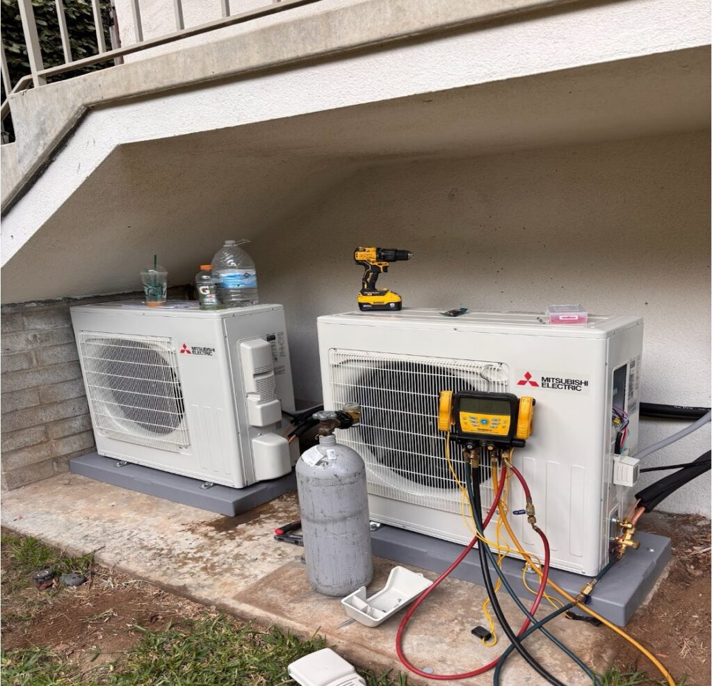 Two outdoor HVAC condenser units are being installed on concrete pads