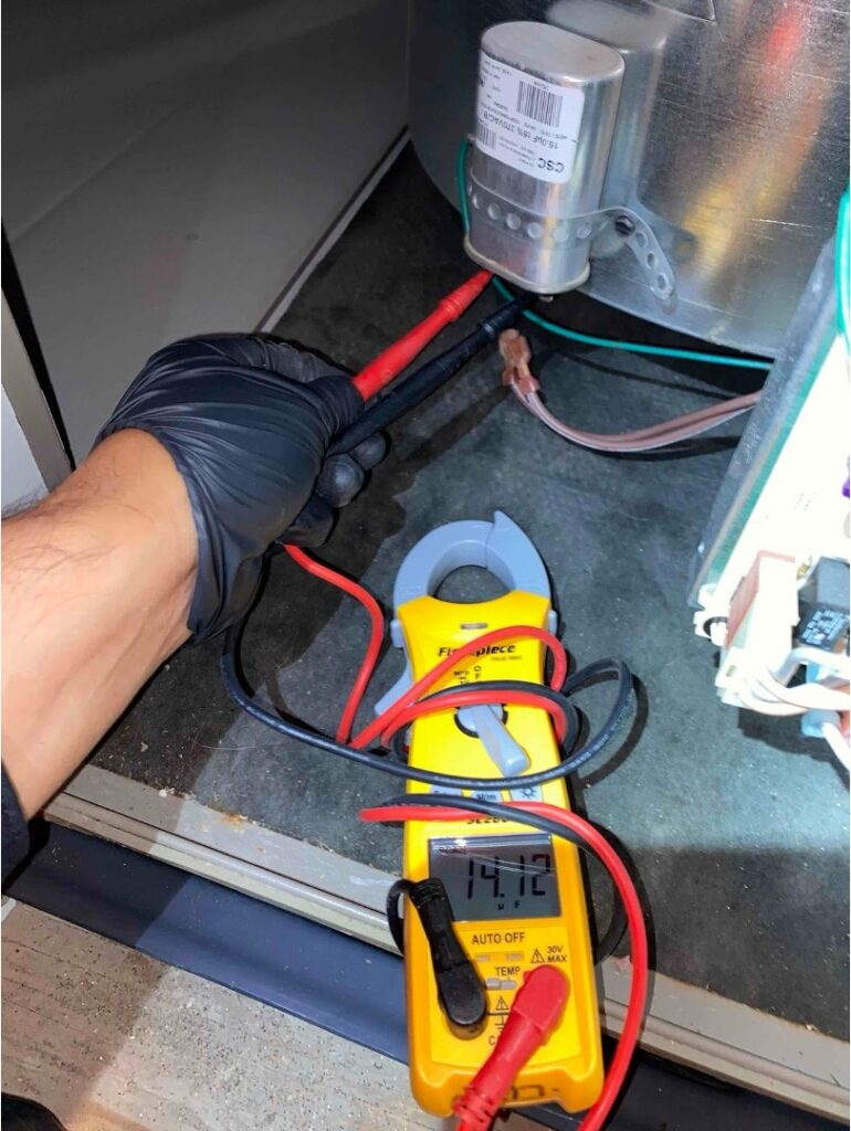 A technician using a clamp meter to test electrical components during a furnace diagnostic in a San Carlos home.