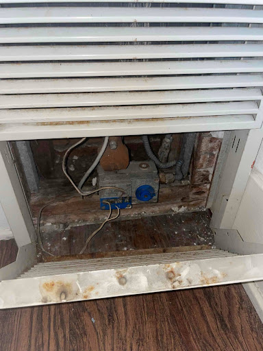 Interior view of a deteriorating old furnace showing rust, corrosion, and worn components.