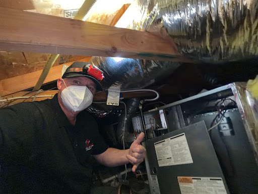Point Loma Home Pros technician inspecting a furnace in a crawl space.