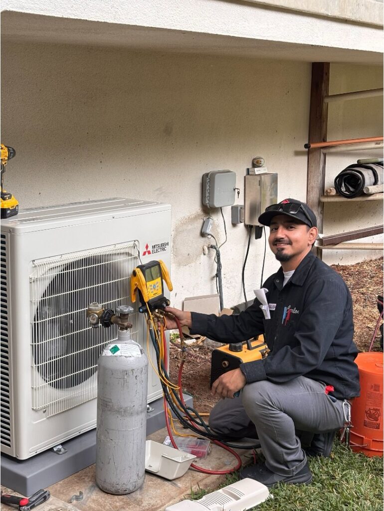 Licensed HVAC technician using refrigerant pressure gauges during an AC diagnostic service call.