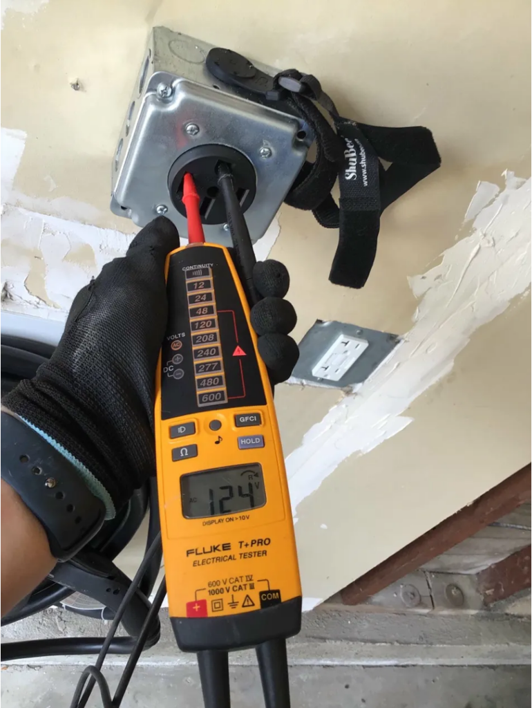 Licensed electrician using a voltage tester to check an electrical junction box in a San Diego home