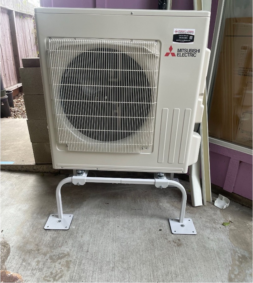 Mitsubishi Electric outdoor mini split unit installed on a wall-mount bracket at a residential home.
