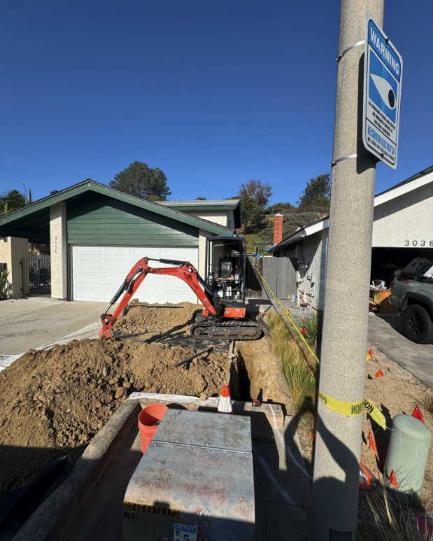 Open trench and mini excavator outside a San Diego home during a residential sewer line replacement