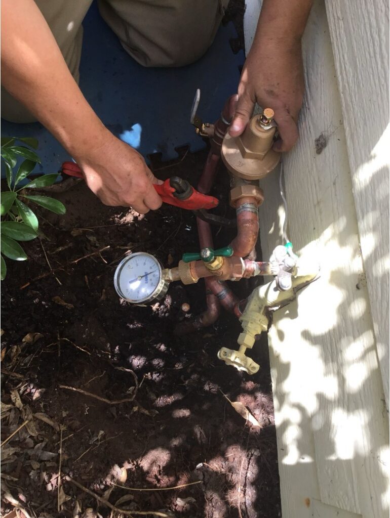 Plumber testing water pressure at the main shutoff, showing hands-on experience