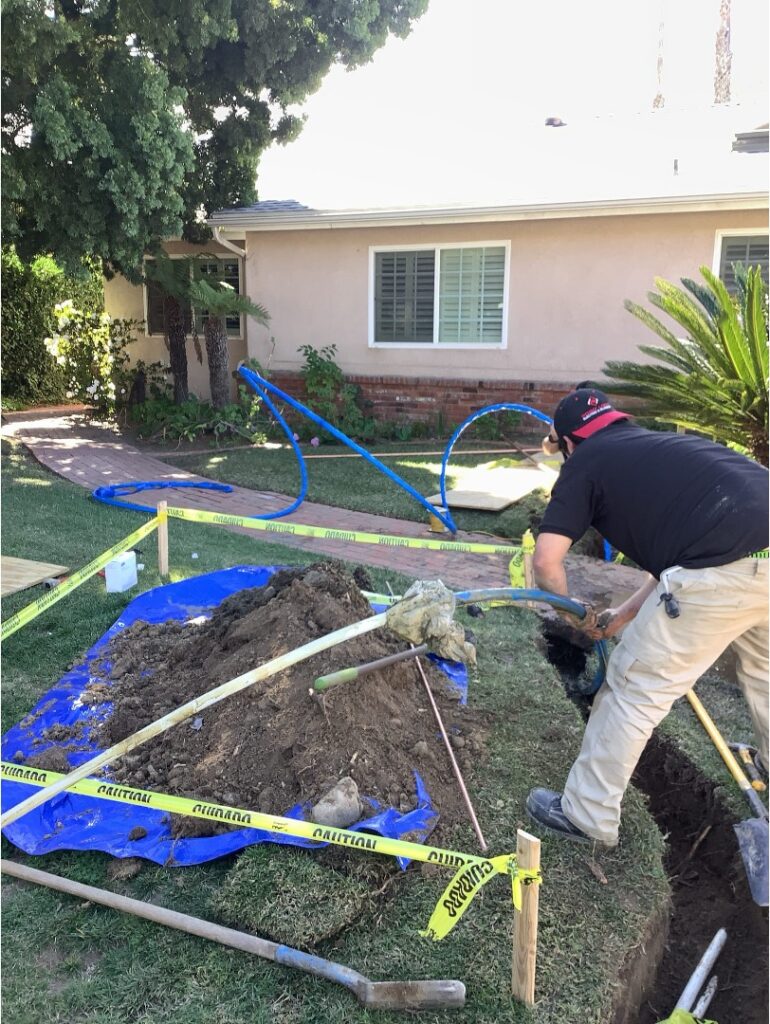 Technician working on a sewer line excavation in a residential San Diego front yard