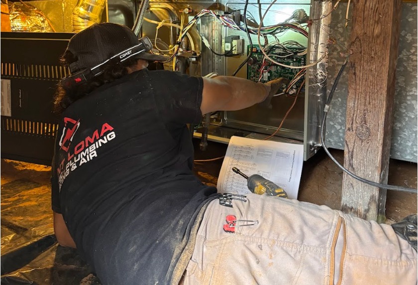 Point Loma technician servicing a water heater's internal wiring while referencing a manual, with tools nearby.