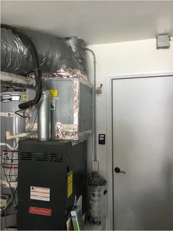 A residential gas furnace installed in a closet beside a water heater.