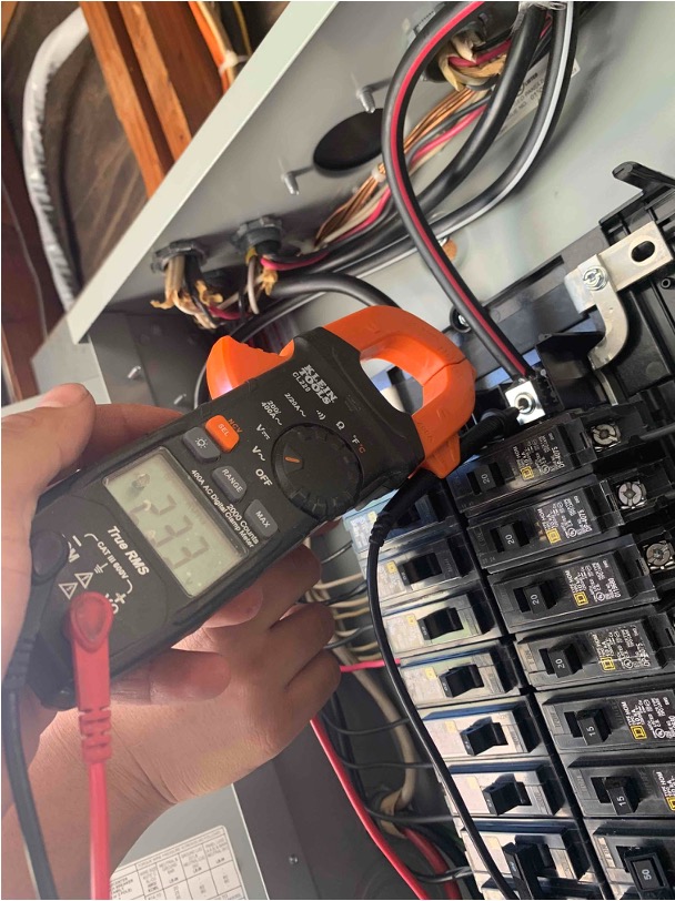Digital clamp meter testing an electric circuit breaker