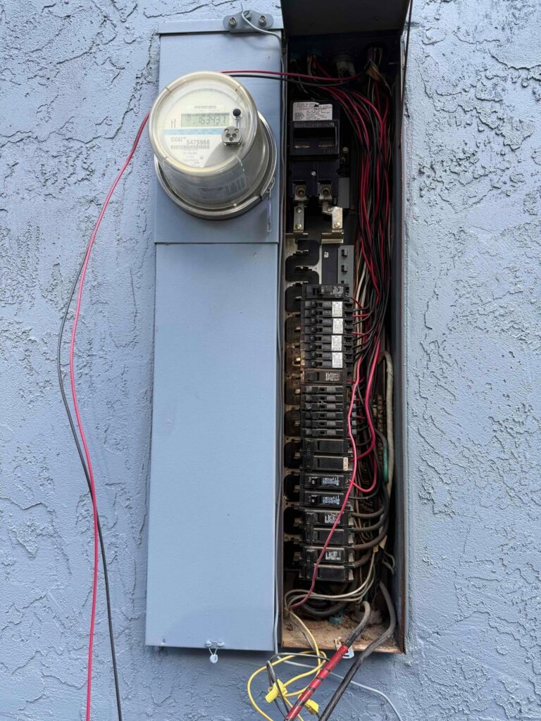 Open residential circuit breaker panel next to an SDG&E electric meter, with breakers and wiring exposed.