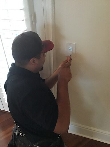 Person adjusting a switch inside a home near a window with blinds