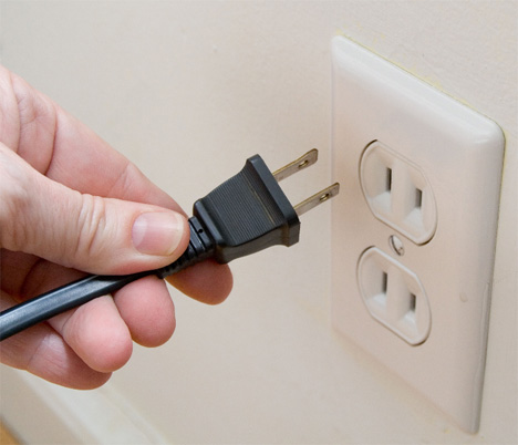 Person holding a plug in front of an outlet