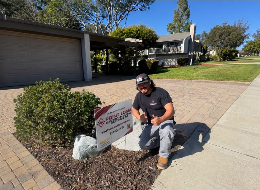 Point Loma Home Pros technician giving thumbs up beside company yard sign outside a residential home