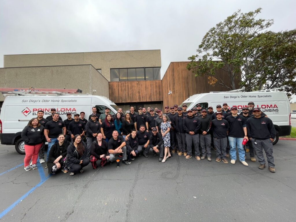 The full Point Loma Home Pros team standing together in front of company vans and the office.
