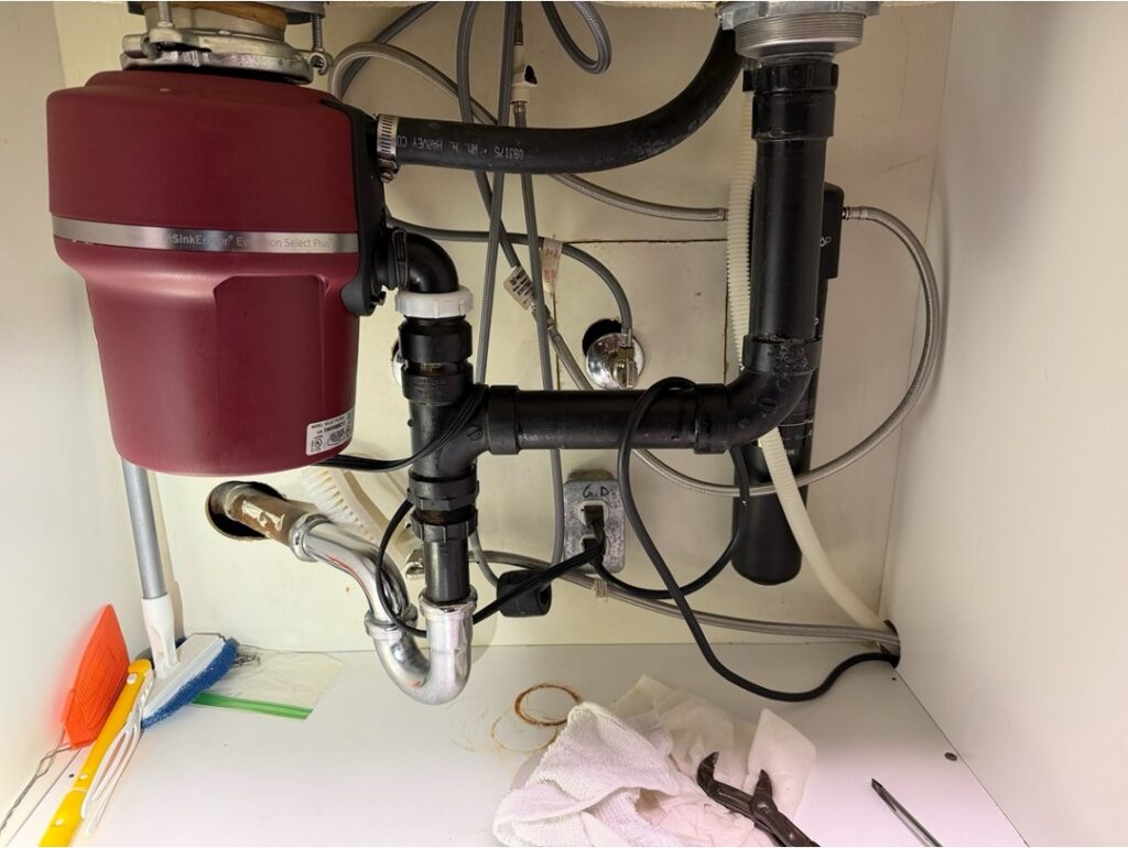 Under-sink plumbing showing a garbage disposal, drain trap, and water supply lines