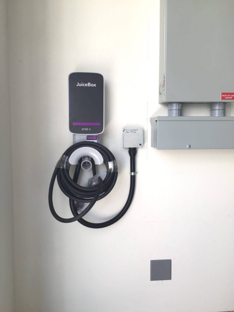 Wall-mounted Level 2 home EV charger installed next to a residential electrical panel.
